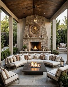 an outdoor living area with couches, tables and a fire place in the center