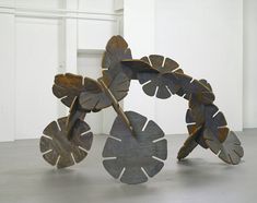 two metal sculptures sitting on top of a cement floor next to each other in front of a white wall