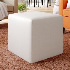 a living room filled with furniture and a white ottoman sitting on top of a carpeted floor