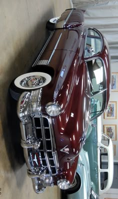 an antique car is parked on the wall next to another classic car in a garage