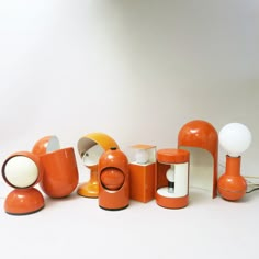 an assortment of orange and white objects on a white surface with one lamp in the middle