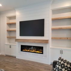 a living room with built in shelves and a flat screen tv mounted on the wall