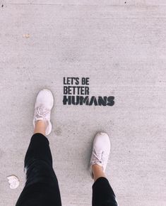 someone standing in front of the words let's be better humans written on concrete