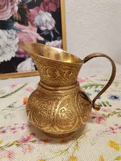 an ornate brass vase sitting on top of a table