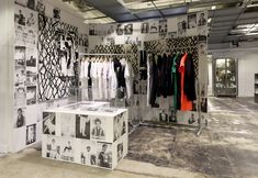 an open closet with clothes hanging on racks and pictures on the wall behind it, all in black and white