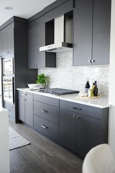 a kitchen with gray cabinets and white counter tops