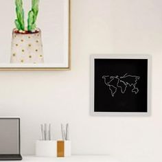 a laptop computer sitting on top of a white desk next to a potted plant