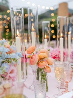 the table is set with candles, flowers and glass vases for an elegant dinner