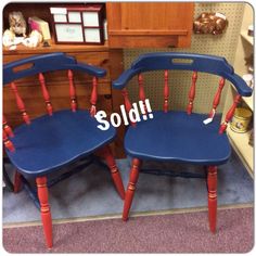 two wooden chairs with red and blue paint on them, one has the word sold