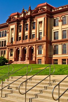 an old building with stairs leading up to it and green grass in the foreground