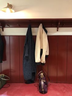 a coat rack with coats hanging on it next to a purse and handbag in a room