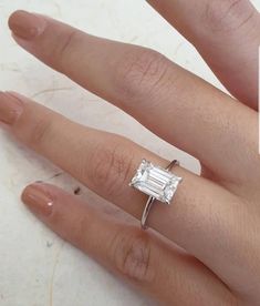 a woman's hand with a ring on it and an engagement ring in the middle