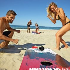 a man and woman on the beach playing with a bean bag game