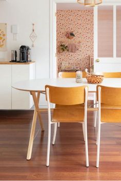 a dining room table and chairs in front of a wall with flowers on the walls