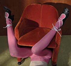 a woman in tights and heels laying on a chair with her legs up to the ground