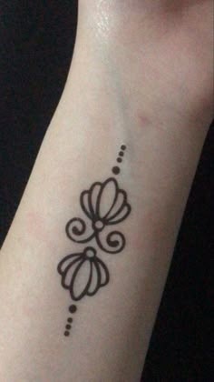 a woman's wrist with a small tattoo on the left side of her arm