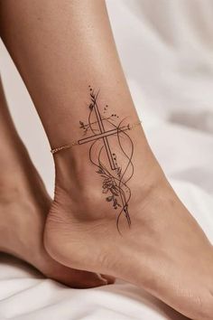 a woman's foot with a cross and arrow tattoo on the bottom of it