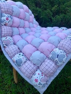 a pink and blue heart shaped chair with pillows on it's back in the grass