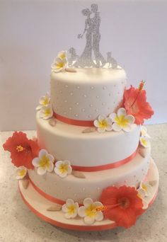 a three tiered wedding cake decorated with flowers and a couple figurine on top