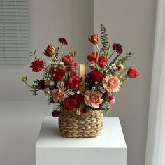 a basket filled with lots of flowers on top of a white table next to a window