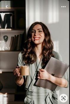 a woman holding a laptop and coffee in her hand