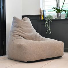 a bean bag chair sitting on the floor in front of a book shelf and window