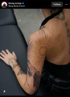 a woman with tattoos on her back and arm is looking at the camera while sitting down