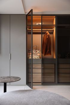 a walk in closet with an oval table and coat hanging on the wall next to it