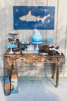 a table topped with cakes and cupcakes on top of a wooden table next to a wall