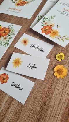 some cards with flowers on them are sitting on a table next to other cards that say names