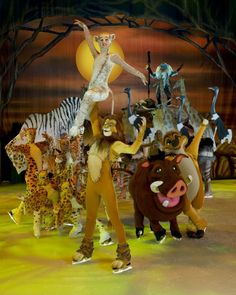 the lion king is surrounded by other animals and people in front of a stage backdrop