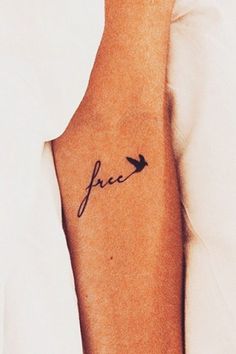 a woman's arm with a small tattoo on it that reads, peace in cursive writing