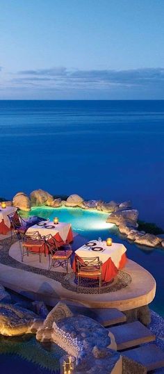 an aerial view of the pool and beach area at night, with umbrellas set up around it