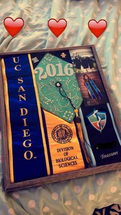 a book with graduation caps on it laying on top of a bed next to hearts