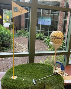 a golf ball on top of a green chair with a hole in the grass next to it