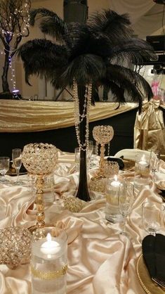 a table topped with lots of glass vases filled with water and candles next to a palm tree