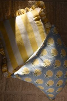 three yellow and white pillows sitting on top of a bed