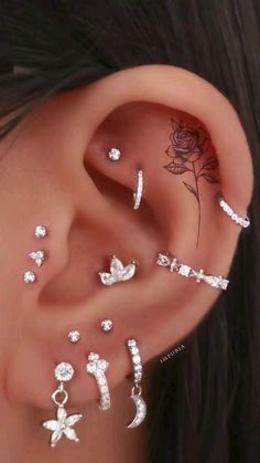 an ear with several different piercings on it and one has a rose in the middle