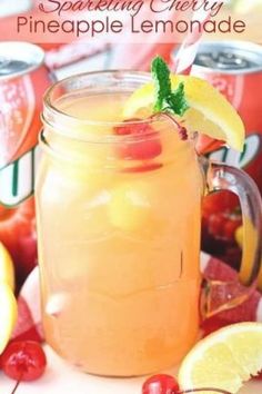 a jar filled with pineapple lemonade sitting next to some sliced apples and cherries