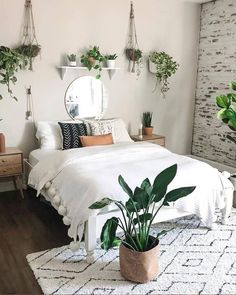 a bedroom with white bedding and plants on the wall, along with a round mirror