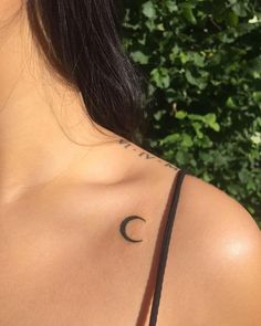 the back of a woman's shoulder with a crescent tattoo on it