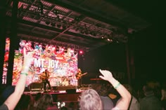 a group of people standing on top of a stage with their hands in the air