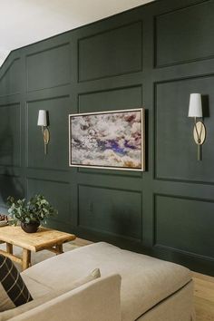 a living room with green walls and white couches in front of a painting on the wall