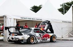 a car that is parked in front of a white tent with people standing around it