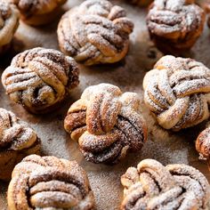 many pastries are covered in powdered sugar on a wooden board with other pastries