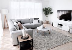 a living room filled with furniture and a flat screen tv mounted on the wall above it