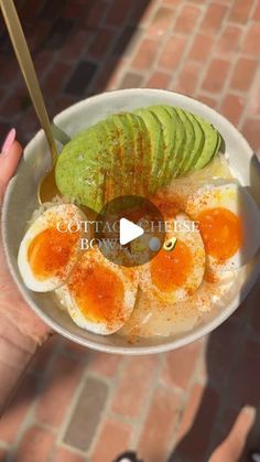 someone holding up a bowl with eggs and avocado