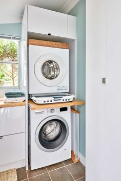 a washer and dryer in a small room with tile flooring on the walls