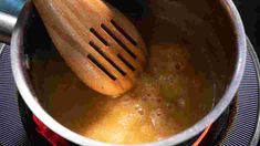 a wooden spoon in a pot on top of a stove burner with boiling water