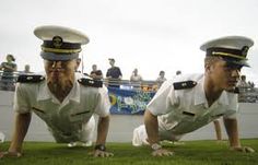 two men in naval uniforms are on the grass